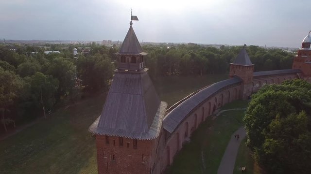Unique aerial flight around tower Veliky Novgorod Kremlin Detinets. Ancient oldest Russian capital. Fortress bank Volkhov River. Drone footage from above. Sunset warm light.