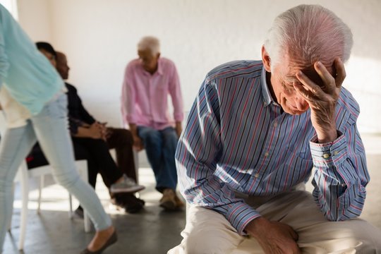 Tensed senior man with friends in background
