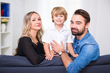 happy family portrait - young couple and cute little son sitting at home