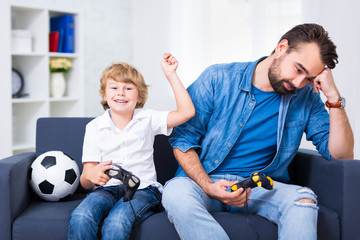 father and son with gamepads playing video game at home