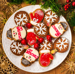 Christmas cookies with festive decoration. Plate with tasty New Year homemade sweets on wooden table. Gingerbread and christmas cookies with festive decor on wooden background.