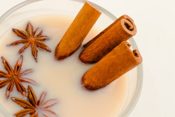 Indian masala tea with spices and milk on white background.