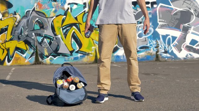 A graffiti artist throws and catches a paint can. 