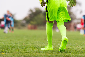 Kids soccer football - little goalkeeper in green goalkeeper jersey at soccer field