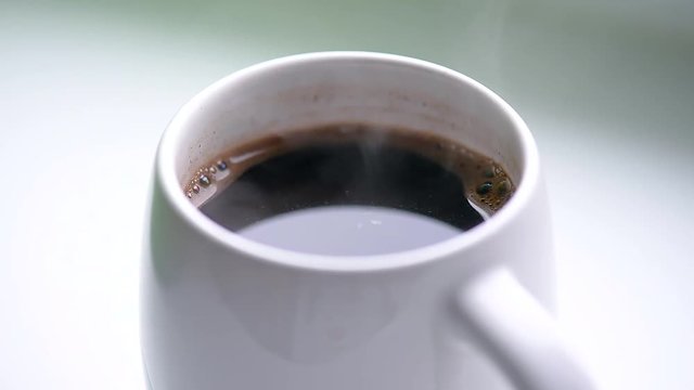 Hot black coffee with the steam in a white mug, morning beverage, video HD 1080