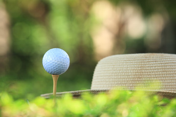  Golf ball on tee ready to be shot and golf hat  background