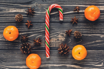 christmas striped candy lollipop  with tangerine and anise pine cones on rustic wooden background top view. xmas seasonal greetings. space for text. winter holidays