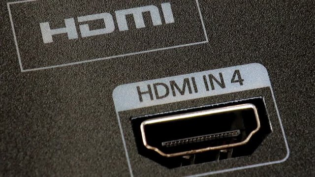 A plugging out a HDMI cord from the socket on the rear panel television, close up. Unconnect a high resolution cable to the monitor.
