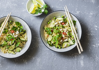 Ramen noodles and pickled cucumber warm salad on a gray background, top view. Asian style food