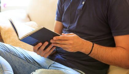 Man reading a book sitting on a sofa at home