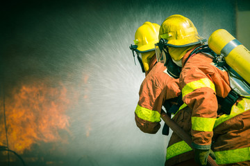 Fototapeta premium 2 firefighters spraying water in cinematic tone