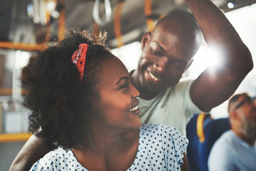 Affectionate young African couple standing together on a bus