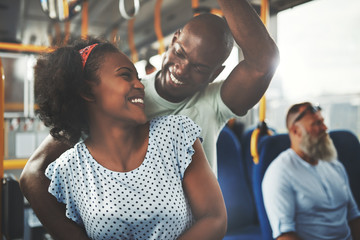 Smiling young African couple standing affectionately together on a bus
