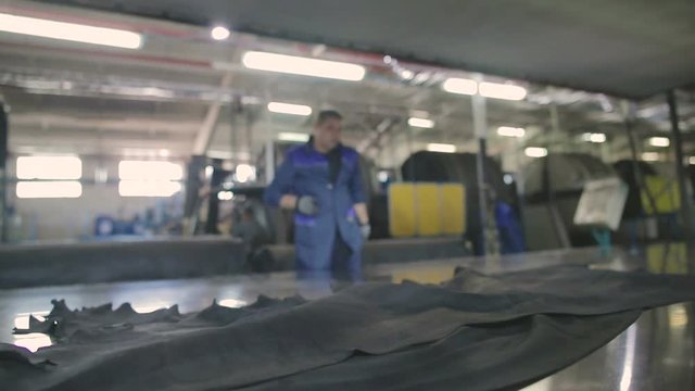 worker throws a piece of leather over the surface of a large hydraulic dryer