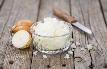White Onions (dices) on wooden background; selective focus