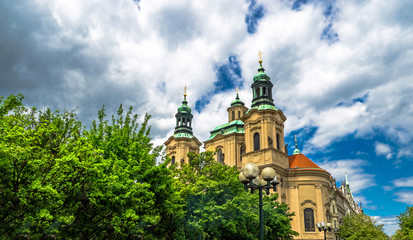 Fototapeta na wymiar Baroque church of St. Nicholas in Malá Strana quarter in the romantic Prague under blue sky. Panoramic of the old city of the hundred towers on a summer day in the capital of the Czech Republic.
