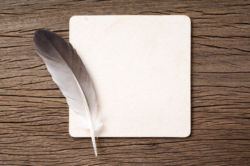 feather and grunge light brown cardboard paper on old wood background