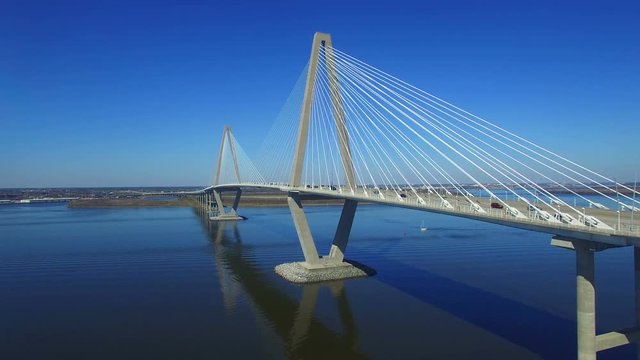 Rising aerial 4k shot of the Arthur Ravenel Jr. Bridge in Charleston South Carolina. Nice reflection on the water with a gorgeous blue sky behind it.