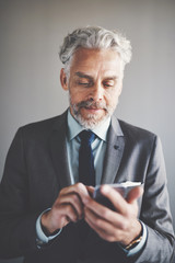 Focused mature businessman send texts on a cellphone