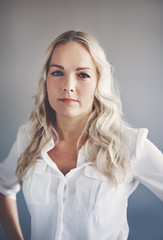 Focused young businesswoman standing alone in an office