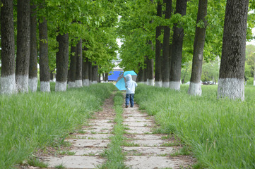 Fototapeta na wymiar Мальчик гуляет с зонтом.