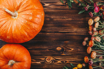 Halloween concept with fresh pumpkins and flowers on the wooden table. Trick or Treat view from above