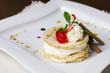 Delicious dessert with white cream, cherries and cinnamon