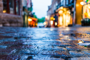 Macro closeup of colorful, vibrant and cobblestone street at night after rain with reflection of...