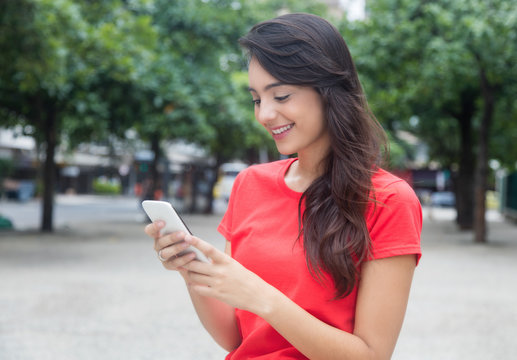 Beautiful girl with red shirt surfing the net with phone