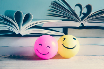 Self made hand drawn smiley face ball in yellow and pink surrounded by a lot of books - Retro...