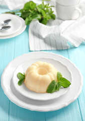 Plate with delicious vanilla pudding on wooden table
