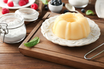 Plate with delicious vanilla pudding on wooden board