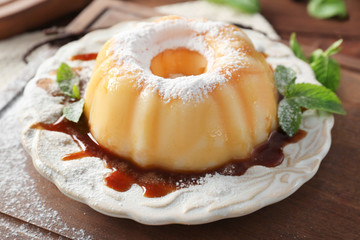 Plate with delicious vanilla pudding on wooden board