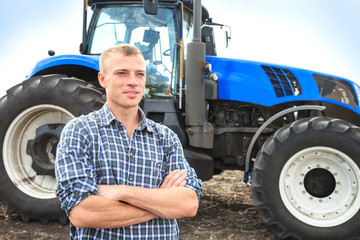 Young attractive man near a tractor. Concept of agriculture.