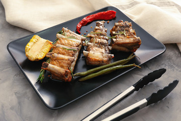 Plate with grilled ribs on table