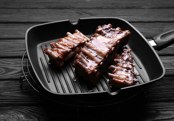 Grill pan with tasty ribs on table