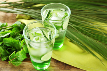 Glasses of cold refreshing drink with green cucumbers on table