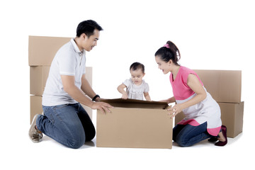 Fototapeta na wymiar Young family unpacking cardboard on studio