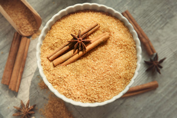 Bowl with cinnamon sugar and sticks on wooden background