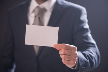 man's hand showing business card isolated on dark background