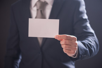 man's hand showing business card isolated on dark background