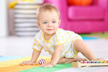 Cute little baby playing with musical instrument at home
