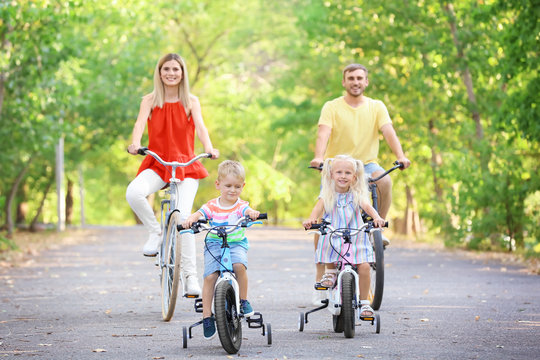 Happy family riding bicycles in park on sunny day
