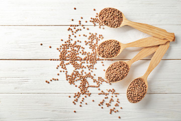 Spoons with healthy lentils on wooden background