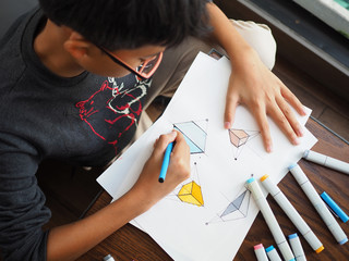 Asian boy sketching with pen and markers