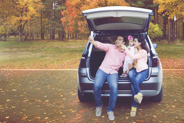 Family taking selfie in car at autumn park