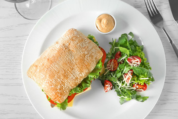 Plate with steak sandwich and vegetable salad on table