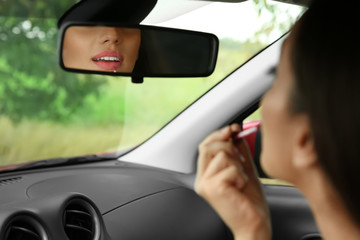 Young woman applying makeup in car