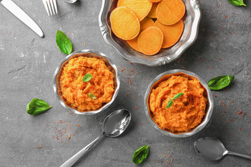 Metal bowls with mashed sweet potato on grey background