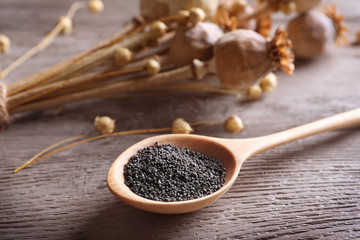 Spoon with poppy seeds on table, closeup
